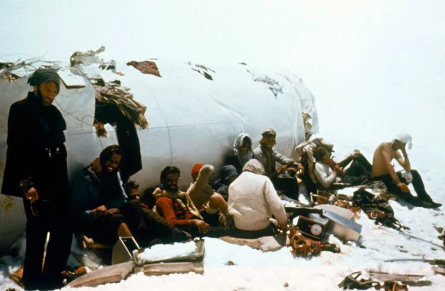 El grupo de sobrevivientes junto al fuselaje, convertido en su único refugio contra el clima extremo y el desolador paisaje andino.